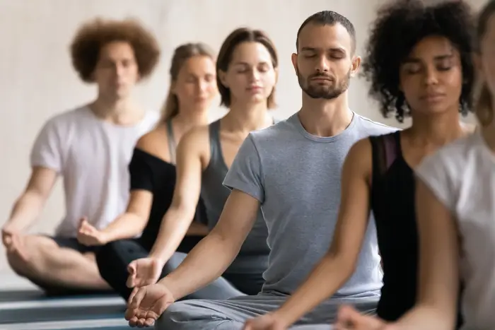 A group of diverse people seated together in yoga poses